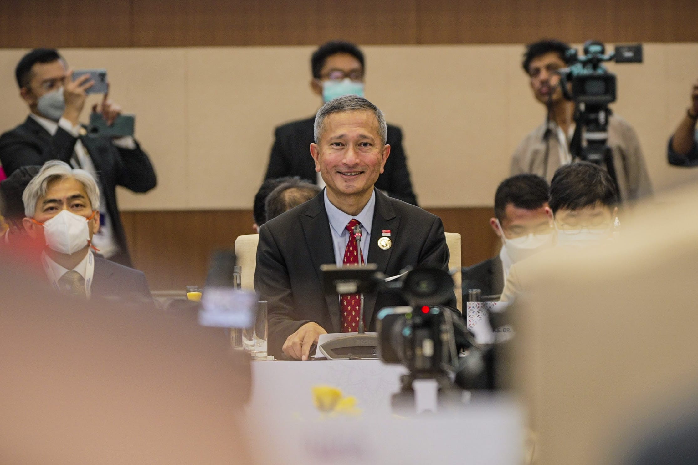 People in business attire sit at a set table with water bottles and menus.